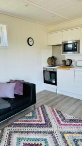 a living room with a black couch and a kitchen at Couston Lakes Resorts in Bathgate