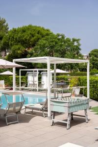 a pool with a table and chairs next to a swimming pool at Hotel Kon Tiki in Numana