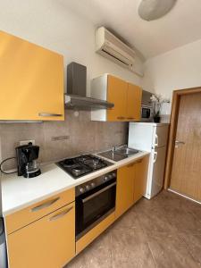 cocina con armarios amarillos y fogones en Apartment Lovre Topic, en Baška Voda