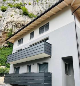 a white building with black windows and a mountain at Residenza The Rock in Nago-Torbole