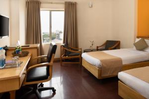 a hotel room with two beds and a desk at Presidency Towers,Kochi in Cochin