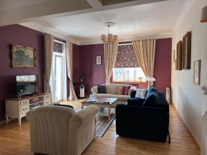 a living room with purple walls and a couch and chairs at Broadway apartament in Šiauliai