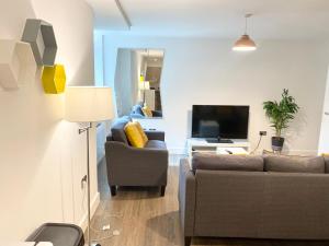 ein Wohnzimmer mit zwei Sofas und einem Fernseher in der Unterkunft Queens House Apartments Coventry in Coventry