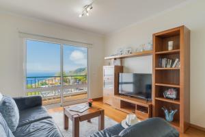 un soggiorno con un divano e una grande finestra di Sunset Horizon by Atlantic Holiday a Estreito de Câmara de Lobos