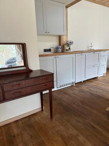a kitchen with white cabinets and a wooden floor at The Lighthouse in Pāvilosta