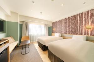 ein Hotelzimmer mit 2 Betten und einem Schreibtisch in der Unterkunft Richmond Hotel Matsumoto in Matsumoto