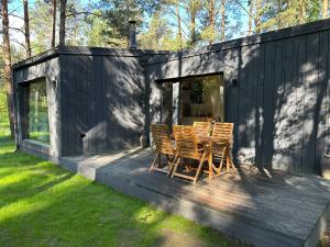 a black cabin with a table and chairs on a deck at The Lighthouse in Pāvilosta
