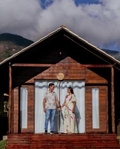 Ein Mann und eine Frau stehen vor einem Haus in der Unterkunft Recanto dos Pássaros in Caparaó Velho