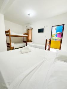 Una habitación blanca con dos camas y un espejo. en Hotel Marujo, en Morro de São Paulo