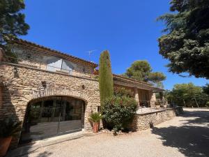 a brick building with a large door and a tree at L'Atelier de la Baronnie - Lubéron in Cabrières-dʼAvignon