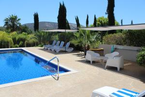 een zwembad met ligstoelen en parasols naast een resort bij St.George's Country Retreat in Limassol