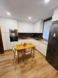 una cucina con tavolo in legno, sedie e frigorifero di A CASA DO LUGAR a Sampaio