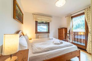a bedroom with a bed and a lamp and a window at Dolomites Dream Arabba in Masarei