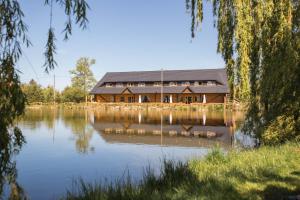 a large wooden house sitting on top of a lake at Noclegi Przycup w Dolinie in Janowice Wielkie