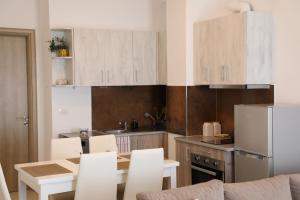 a kitchen with white cabinets and a table and chairs at Saranda Apartaments Meta in Sarandë