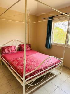 1 dormitorio con cama con dosel y sábanas rosas en la villa somone, en Somone