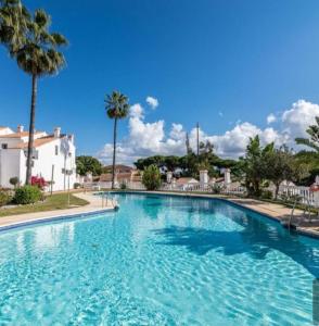 a swimming pool with blue water and palm trees at casa caravane in Benalmádena