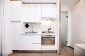 cocina blanca con fregadero y fogones en Design Apartment - Milano City Center - Duomo, en Milán