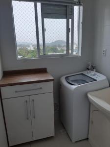 a bathroom with a washing machine and a window at Apartamento Beto Carrero Centro Penha SC in Penha