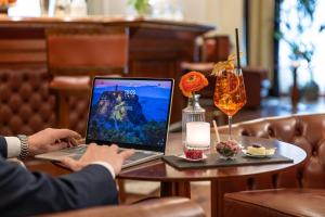 una persona sentada en una mesa con un ordenador portátil en Starhotels Majestic en Turín