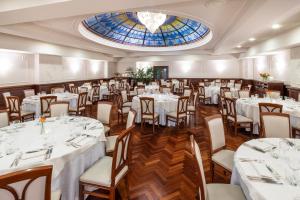uma sala de jantar com mesas e cadeiras brancas e uma janela em Starhotels Majestic em Turim