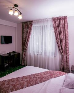 a bedroom with a bed and a window with curtains at Hotel Transalpin in Obarsia-Lotrului +33 photos