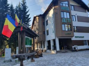 a building with two flags in front of it at Hotel Transalpin in Obarsia-Lotrului