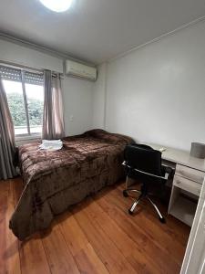 een slaapkamer met een bed, een bureau en een stoel bij Apartamento Pôr do Sol in Porto Alegre