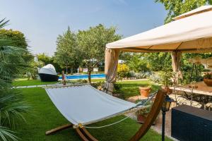 a hammock in a yard under an umbrella at Au Jardin fleuri in San Giovanni Lupatoto