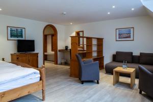 sypialnia z łóżkiem, kanapą i telewizorem w obiekcie Hotel Hofgut Sternen w mieście Breitnau
