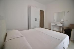 a white bedroom with a white bed and a chair at Saranda Apartaments Meta in Sarandë