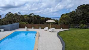 a swimming pool with two chairs and an umbrella at Villa Capelinhos in Capelo