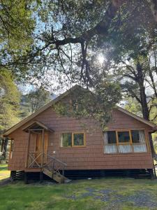 una pequeña casa marrón con un árbol en El Pangue Lodge en Puerto Puyuhuapi