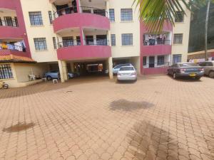 a parking lot in front of a pink building at Kaimbu Road Zone Apartments in Kiambu