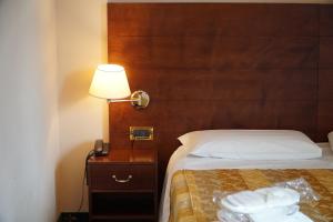 ein Hotelzimmer mit einem Bett mit einer Lampe und Handtüchern in der Unterkunft Hotel President in Montecatini Terme