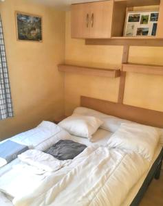 Cama en habitación con sábanas y almohadas blancas en Bungalow de 2 chambres a Cauterets a 900 m des pistes avec jardin amenage et wifi en Cauterets
