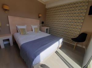 a bedroom with a large bed and a chair at Hôtel Ker-Noyal Quiberon Plage in Quiberon