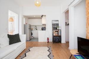 a living room with a white couch and a kitchen at Alba Beach Boutique Apartment in Estoril