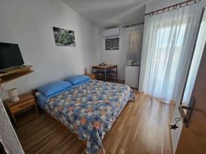 sypialnia z łóżkiem z niebieskimi poduszkami i telewizorem w obiekcie Apartman Dino w mieście Murter