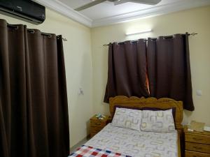 - une chambre dotée d'un lit avec des rideaux bruns dans l'établissement Résidence lynda prestige Ouaga 2000, à Ouagadougou