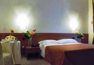 una camera d'albergo con letto e tavolo con fiori di Hotel Villa Giusy a Castellaneta Marina