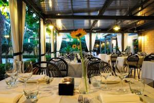 a table with glasses and a vase with a flower on it at Hotel Villa Giusy in Castellaneta Marina
