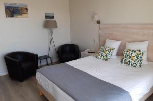 a bedroom with a white bed with two pillows at Hôtel Ker-Noyal Quiberon Plage in Quiberon