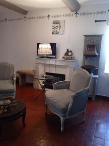a living room with two chairs and a fireplace at Le Mas des Baux in Bédoin