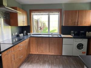 a kitchen with a sink and a washing machine at Barnbackle Cottage in Shawhead