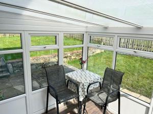 a screened in porch with a table and chairs at Barnbackle Cottage in Shawhead +6 photos