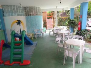 ein Restaurant mit Tischen, Stühlen und einer Rutsche in der Unterkunft Hotel Pousada Portal da Palmeira in Ubatuba