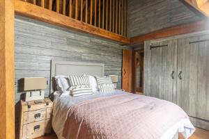 1 dormitorio con 1 cama y pared de madera en Bailiffs Cottage, en Colchester