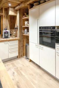 - une cuisine avec des appareils blancs et des murs en bois dans l'établissement Chalet de 5 chambres avec vue sur la ville terrasse amenagee et wifi a Cordon, à Cordon