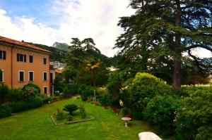 a garden with trees and bushes and a building at Casa Gabry Bouganville in Toscolano Maderno